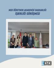 Bir masa etrafında beş kişilik bir grup, ofis ortamında poz veriyor. Arka planda Türkiye bayrağı ve Milli Eğitim Bakanlığı (MEB) bayrağı yer almakta. Duvarın üzerinde iki adet resmi portre bulunuyor. Masanın üzerinde evraklar ve çeşitli belgeler var. Üst kısımda büyük harflerle "MEB ÖĞRETMEN AKADEMİSİ BAŞKANLIĞI İŞBİRLİĞİ GÖRÜŞMESİ" yazıyor. Fotoğrafın alt sağ köşesinde ise "EGED" logosu yer almakta.
