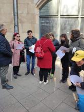 Rehber anlatım yaparken, Elif, Ali,  Zeynep, Ülkü, A4 kağıt boyutunda Braille haritalar ellerinde, yanlarında farklı ülkelerden katılımcılar daire şeklinde birlikte durup rehberin anlatımını dinlemekteler.